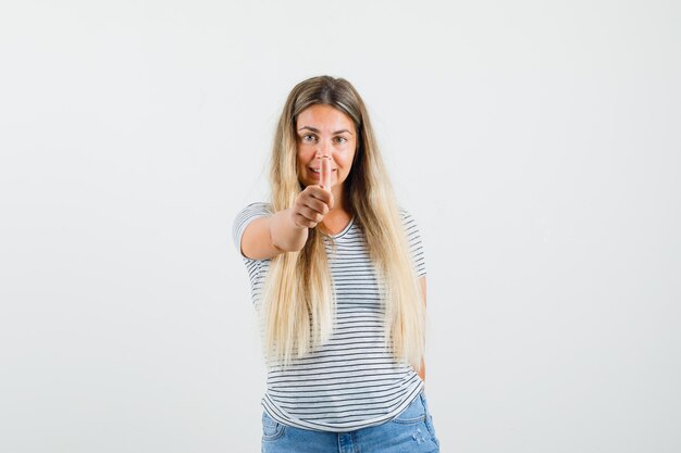 Blonde dame die duim in t-shirt toont en blij, vooraanzicht kijkt.