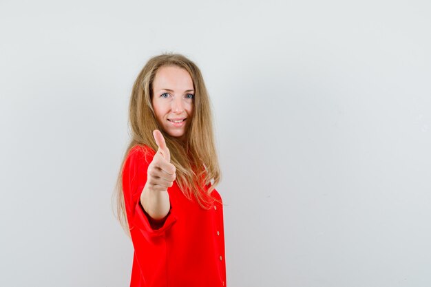 Blonde dame duim opdagen in een rood shirt en er zelfverzekerd uitzien,