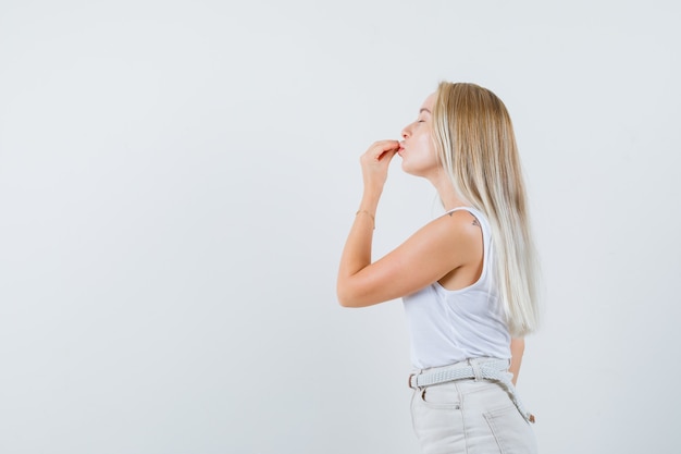 Blonde dame in hemd, broek die heerlijk gebaar toont en verrukt kijkt.