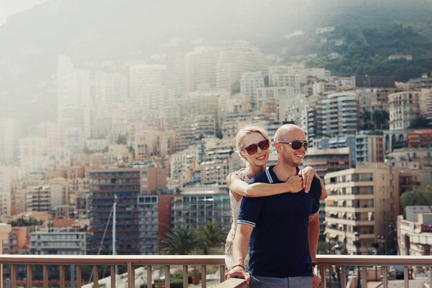 Blonde dame knuffelt kaalkop man met grote cityscape achter de