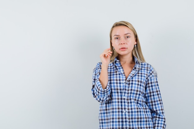 Blonde dame poseren terwijl je in een casual shirt staat en er verstandig uitziet