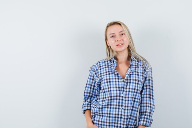 Blonde dame poseren terwijl ze in een geruit overhemd staat en er zelfverzekerd uitziet