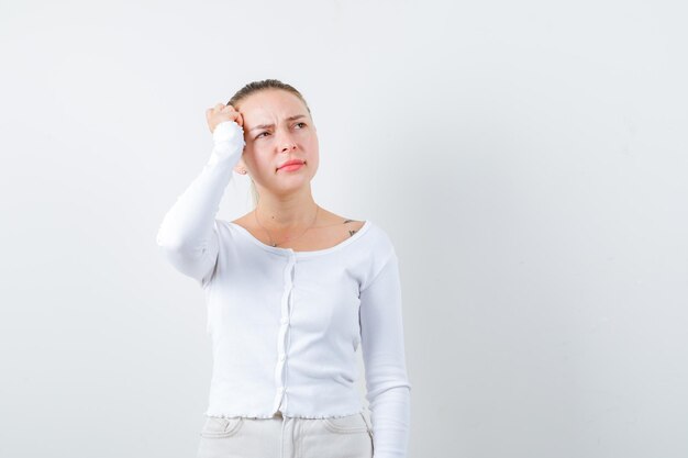 Blonde dame probeert iemand op een witte achtergrond te herdenken