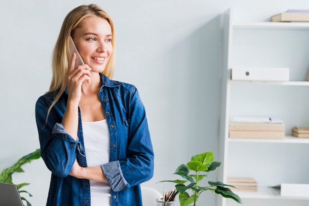 Gratis foto blonde die op telefoon in bureau spreekt