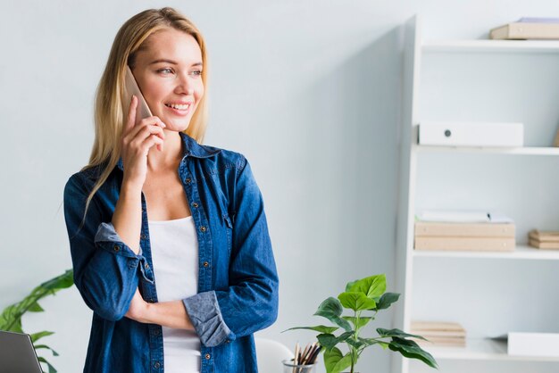 Blonde die op telefoon in bureau spreekt