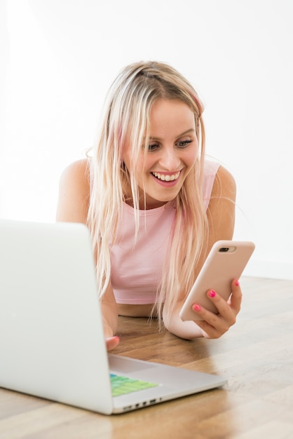 Blonde influencer met behulp van smartphone op de vloer