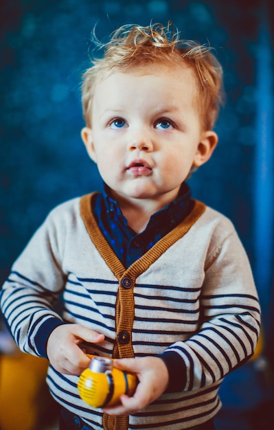 Blonde jongen met blauwe ogen staat in een blauwe kamer