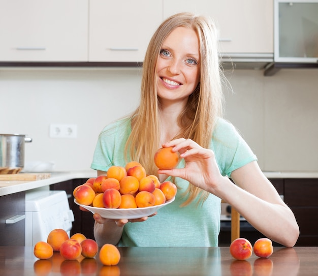 blonde langharige meisje met abrikozen in huis keuken