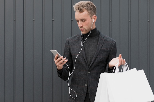 Blonde man in het zwart kijken naar smartphone