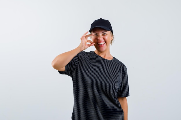 Blonde rijpe vrouw in een zwart t-shirt en een zwarte pet