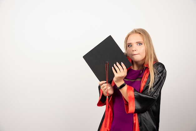 Blonde student houdt haar vast en kijkt naar voren op wit.