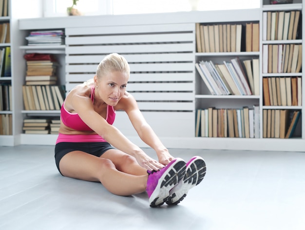 Blonde vrouw atleet doet zich thuis het uitrekken