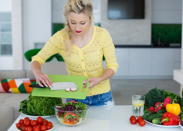 blonde vrouw bereidt salade voor in de keuken