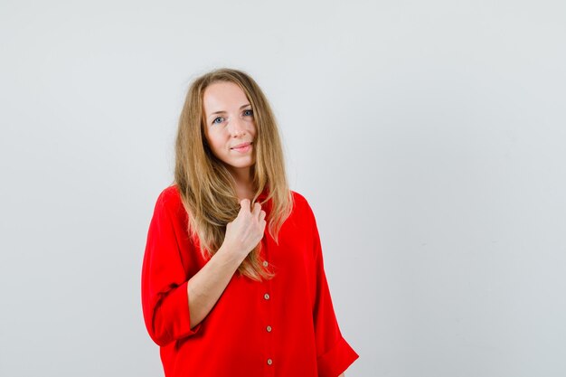 Blonde vrouw camera in rood shirt kijken en er mooi uitzien,