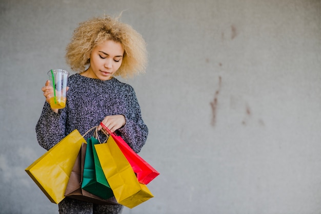 Blonde vrouw die drank en zakken houdt