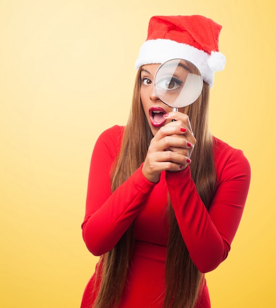 Blonde vrouw die een vergrootglas met een gele achtergrond