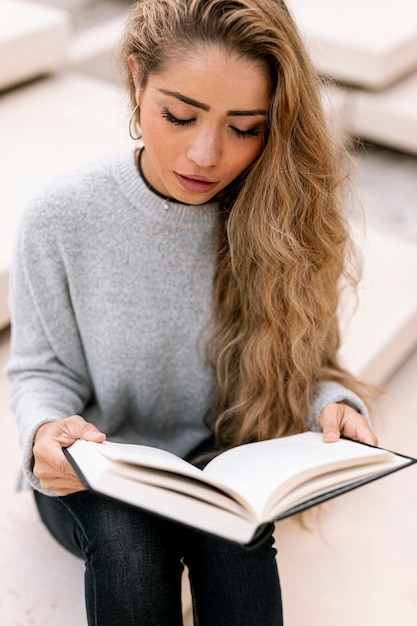 Blonde vrouw die haar boek leest