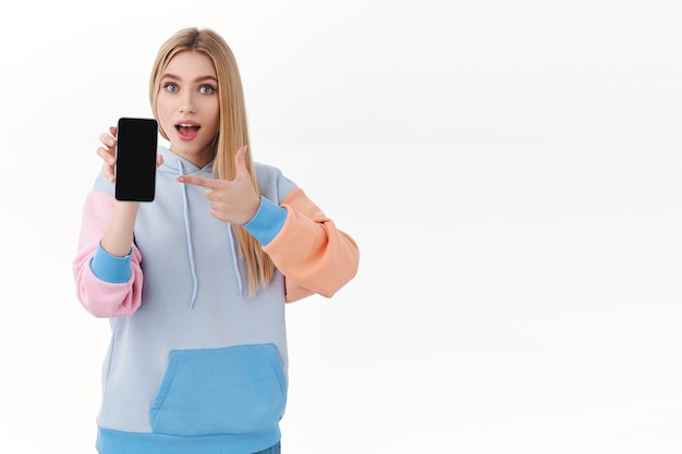 Blonde vrouw die het smartphonescherm toont