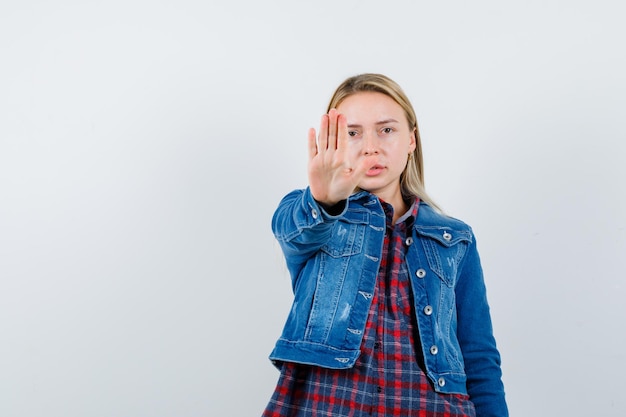 Gratis foto blonde vrouw die stopgebaar in overhemd, jasje toont en resoluut kijkt.