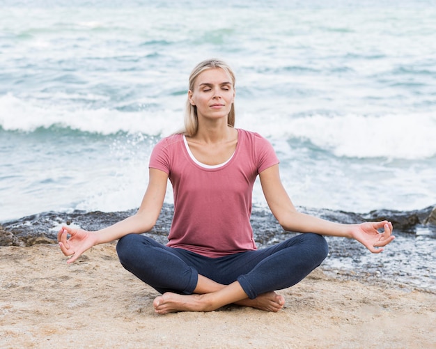 Gratis foto blonde vrouw doet yoga op het strand