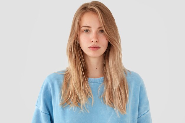 Blonde vrouw in blauw shirt poseren