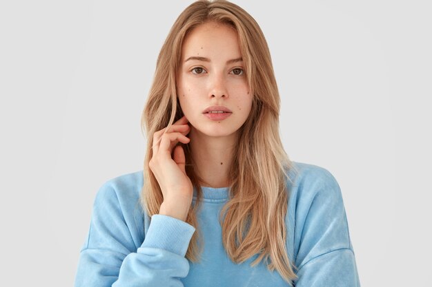 Blonde vrouw in blauw shirt poseren