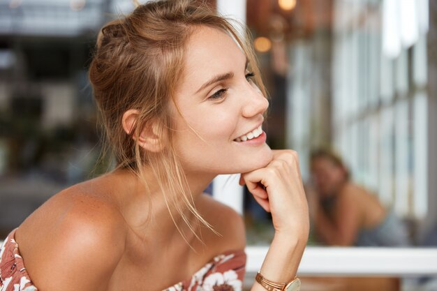 Blonde vrouw in gebloemde jurk in café