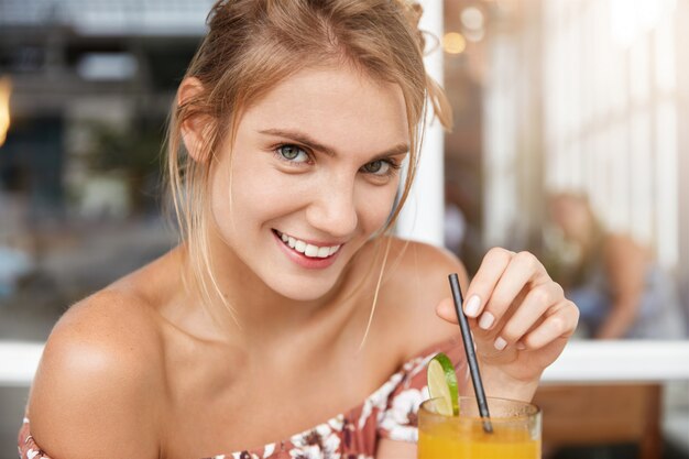 Blonde vrouw in gebloemde jurk in café