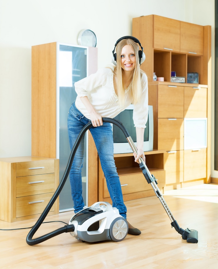 Gratis Foto blonde vrouw in hoofdtelefoon schoonmaken met stofzuiger