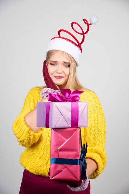 Blonde vrouw in kerstmuts kijken naar kerstcadeaus.