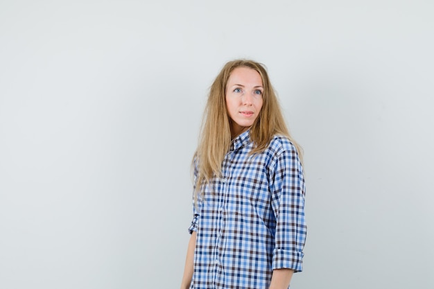 Blonde vrouw in shirt wegkijken en dromerig kijken,