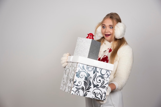 Blonde vrouw in witte trui kijken naar kerstcadeaus.