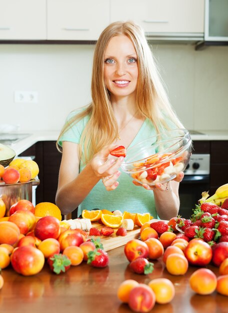 Gratis foto blonde vrouw koken fruitsalade