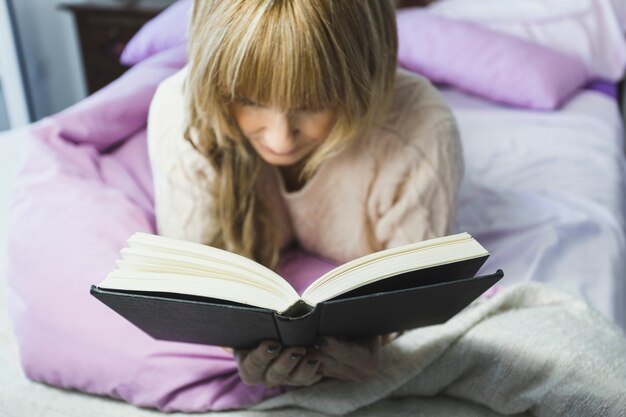 Blonde vrouw leesboek in bed