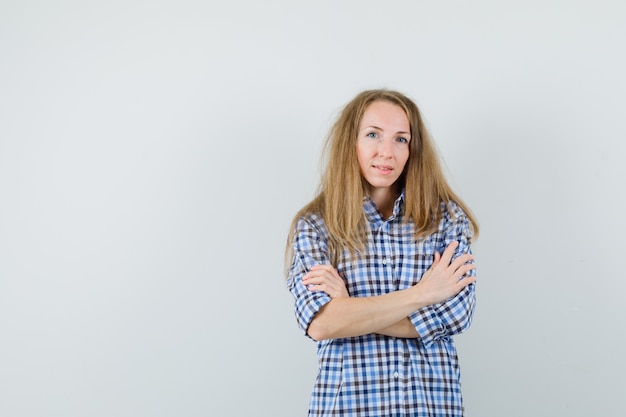 Blonde vrouw met gekruiste armen in shirt en op zoek zelfverzekerd.