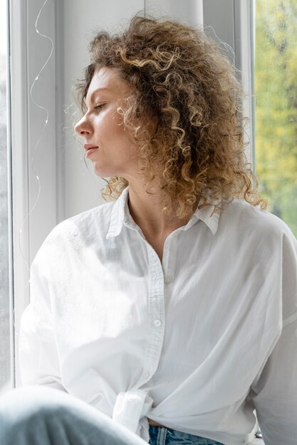 Blonde vrouw met krullend haar thuis ontspannen