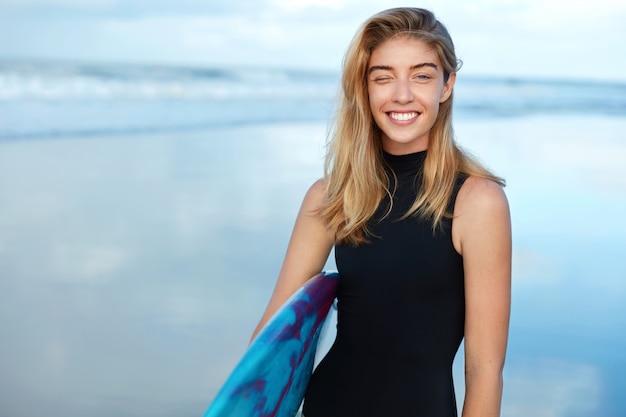 Blonde vrouw met surfplank op strand