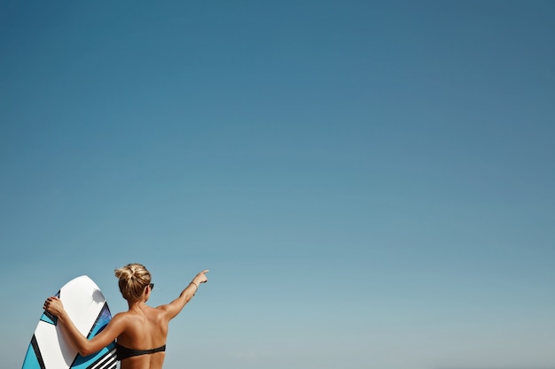 Blonde vrouw op het strand met surfplank