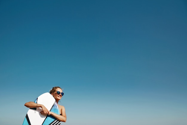 Blonde vrouw op het strand met surfplank