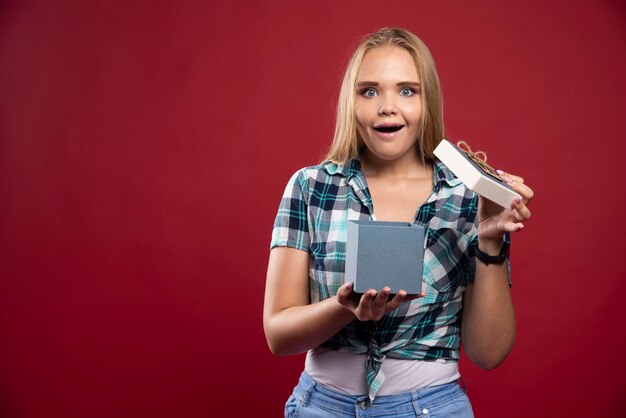 Blonde vrouw wordt verrast bij het openen van een geschenkdoos.