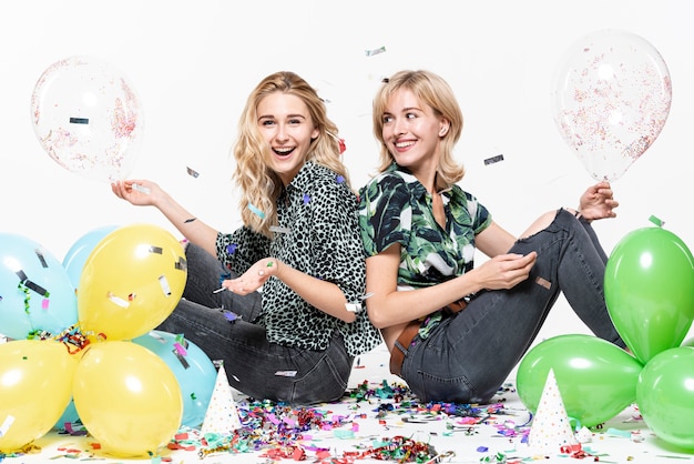 Blonde vrouwen omringd door confetti en ballonnen