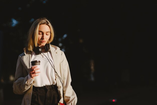 Blonde wandelingen in de zomer stad met een kopje koffie