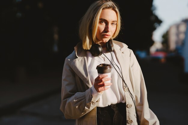 Blonde wandelingen in de zomer stad met een kopje koffie