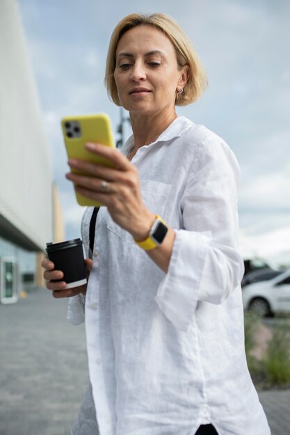 Blonde zakenvrouw die haar telefoon controleert