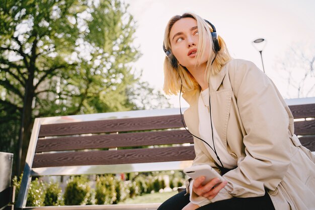 Blonde zittend op een bankje met mobiele telefoon