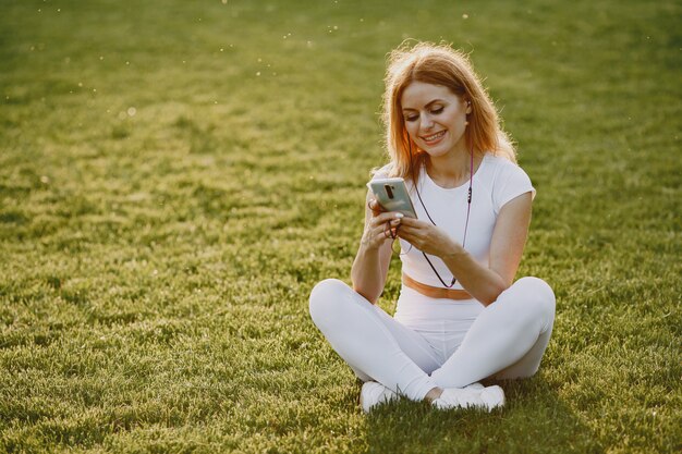 Blonde zittend op een gras met koptelefoon