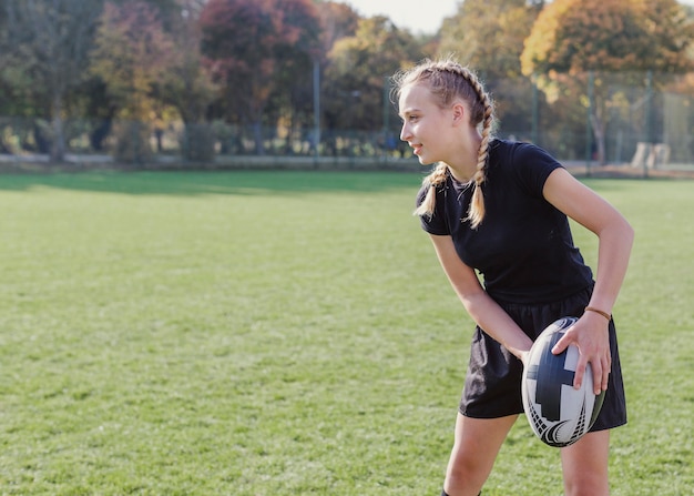 Blondemeisje die een rugbybal voorbereidingen treffen te werpen