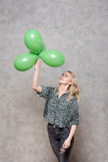 Blondevrouw die groene ballons bekijken