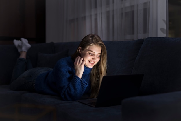 Blondevrouw die op laag met laptop leggen