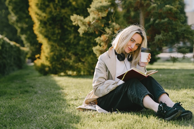 Gratis foto blondezitting op een gras met hoofdtelefoons